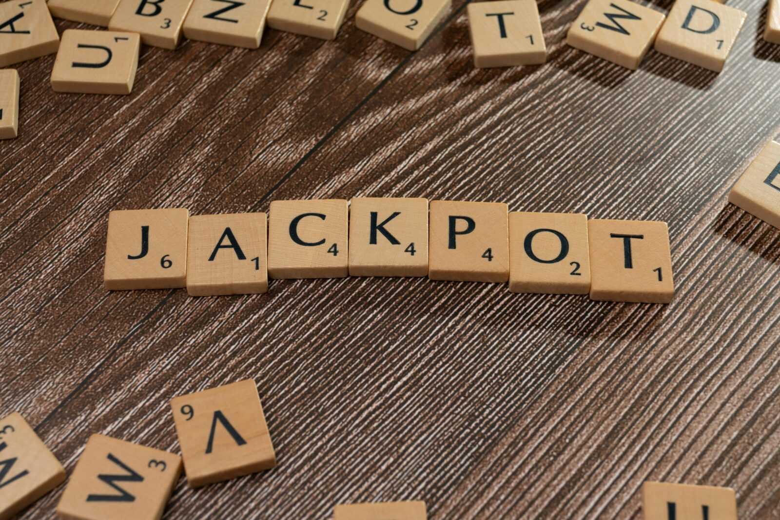 Wooden letter tiles spelling 'JACKPOT' on a textured wooden surface, representing winning or success.
